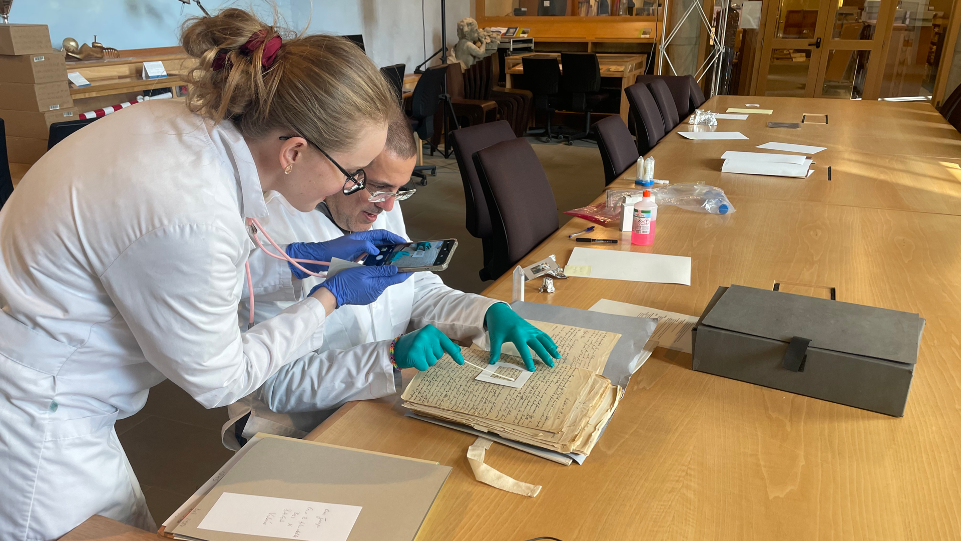 Two scientists taking microbial samples from a historical document at the HAEU