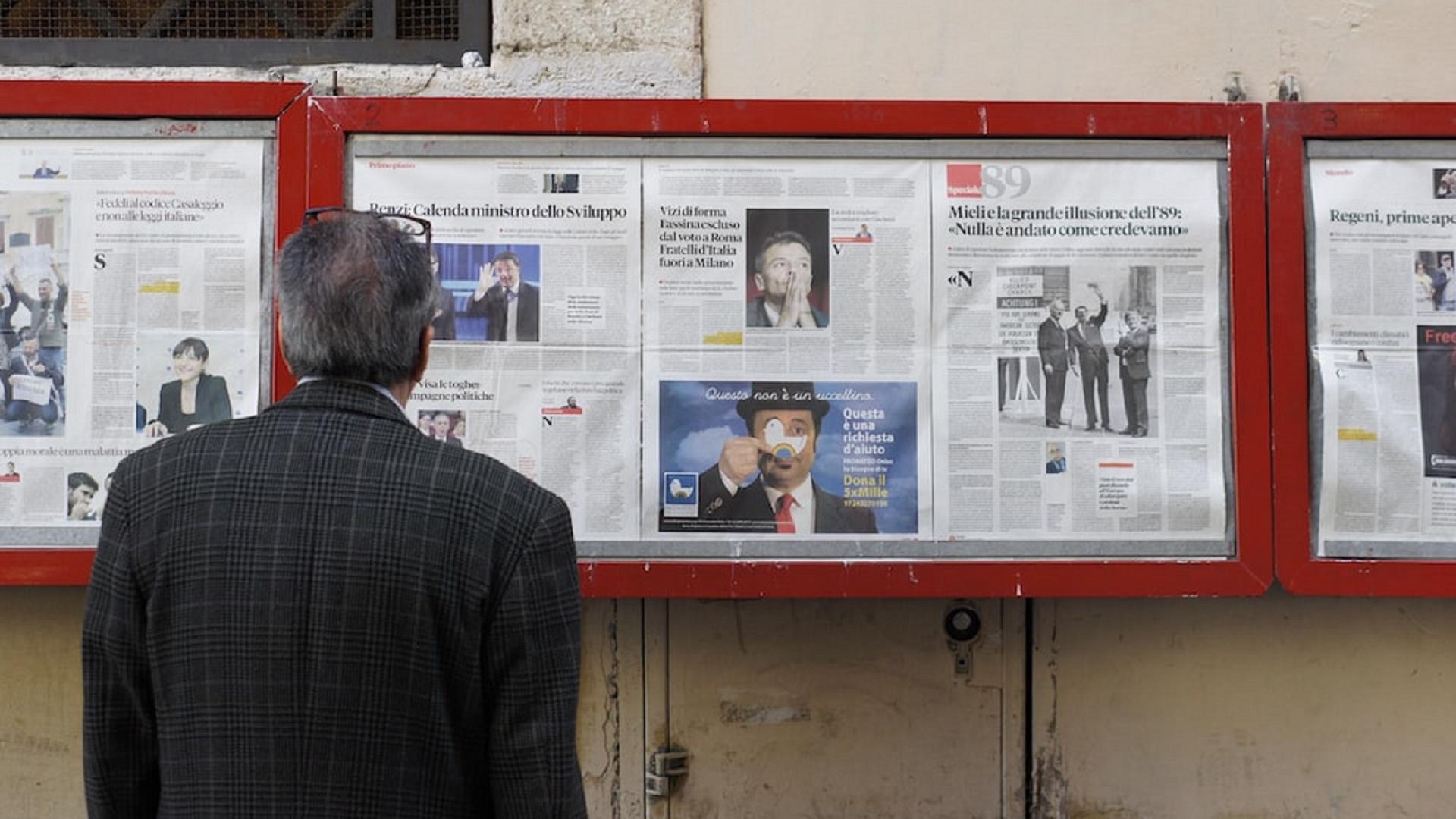 Man looking reading Italian newspapers on a shop-window advertising. Author: Filip Mishevski