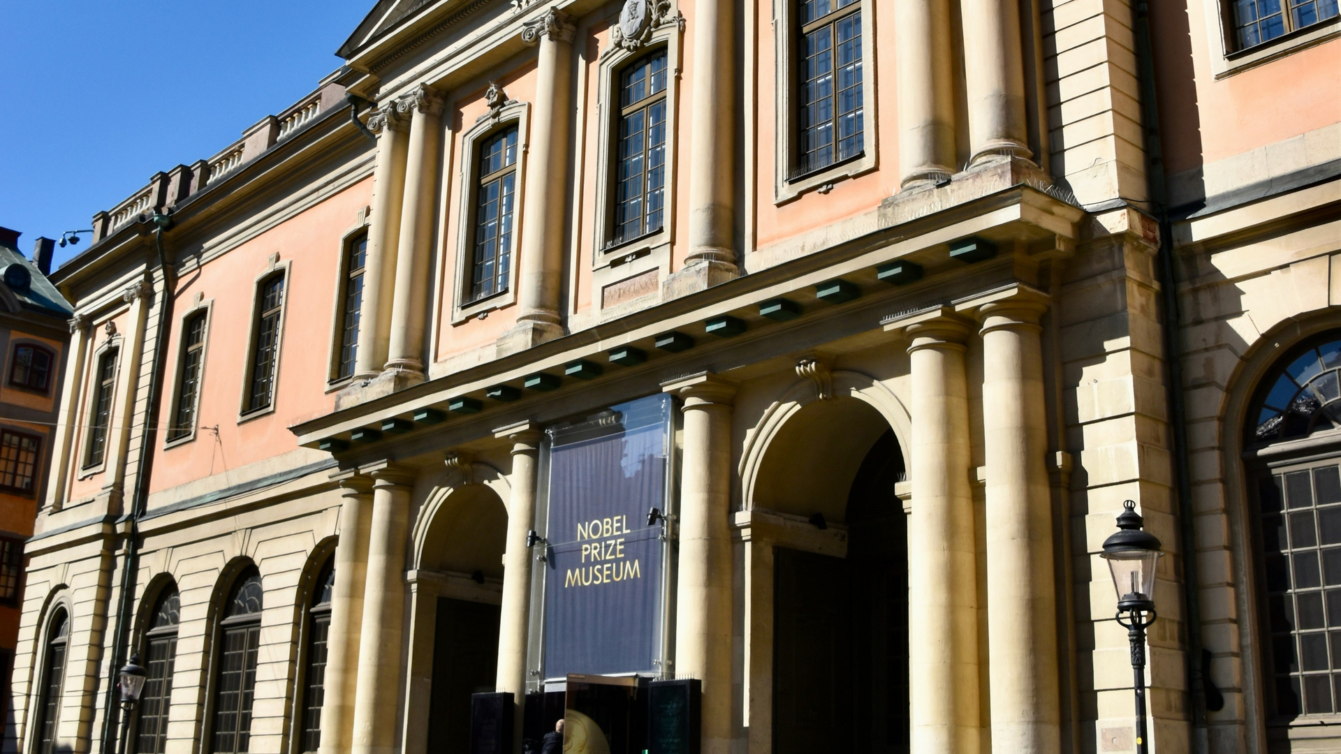 A grand classical building with people on a cobblestone street