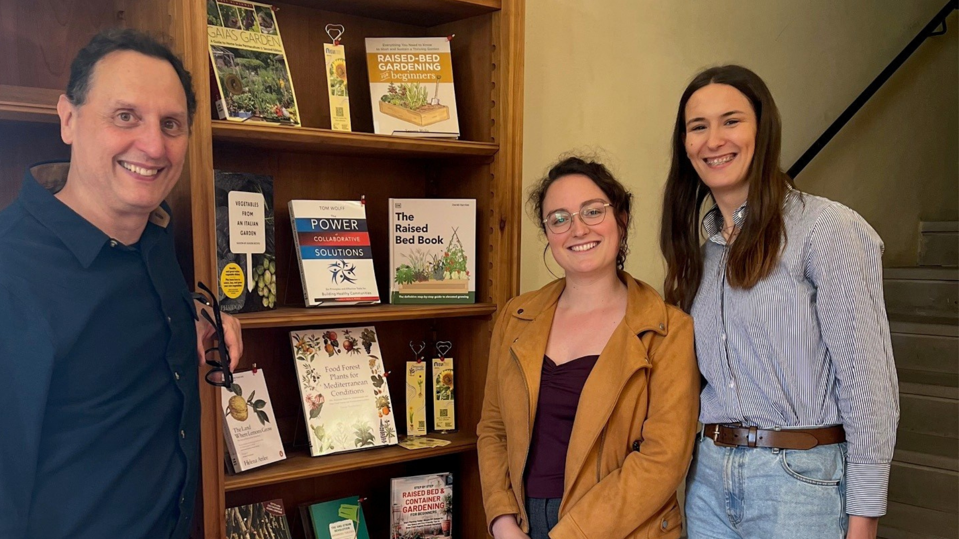Three people beside a library display of books.