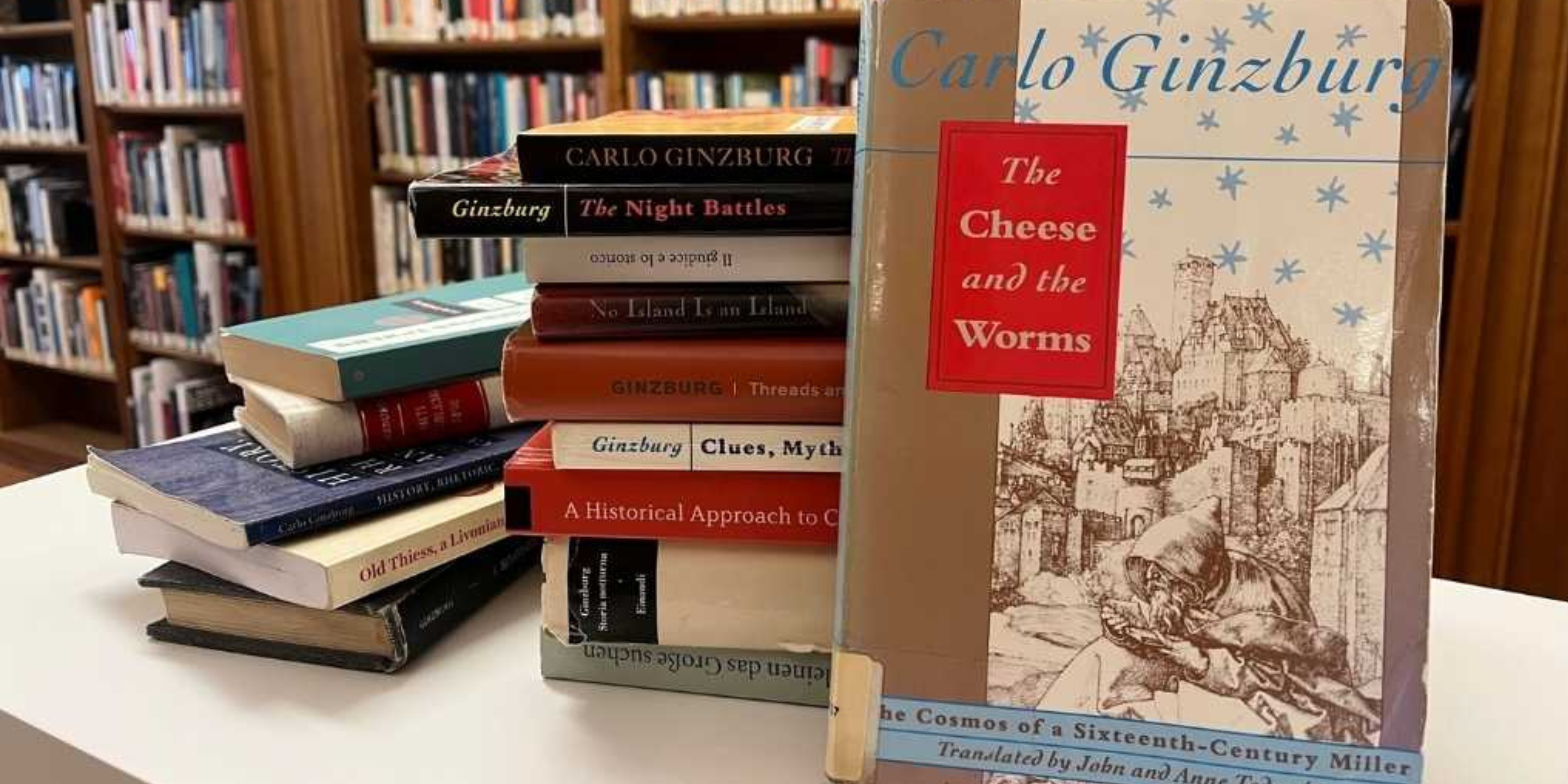 Book display featuring Carlo Ginzburg’s The Cheese and the Worms with stacked books in a library setting. 