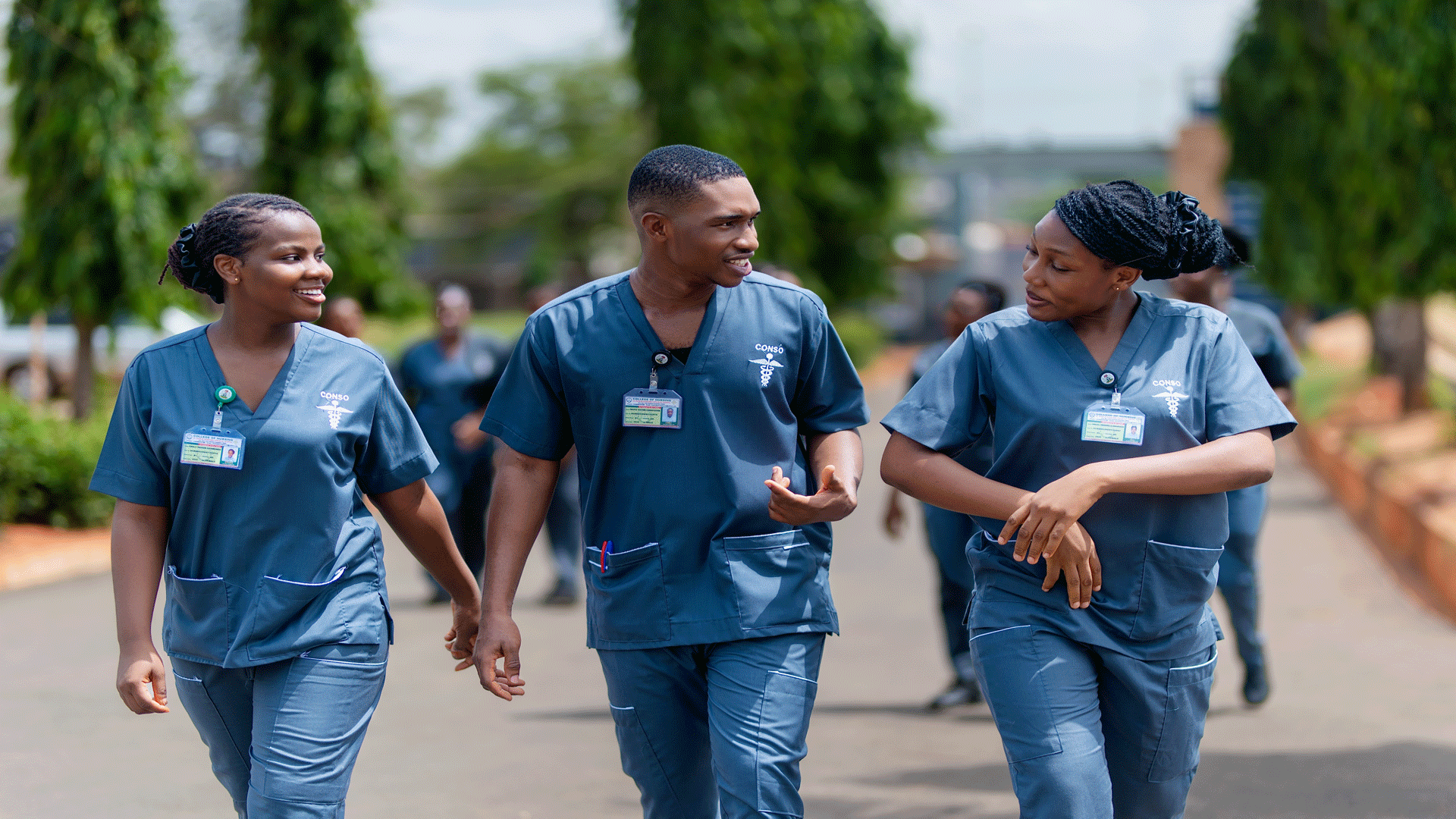 Three young Nigerian medical students walking, talking, and smiling