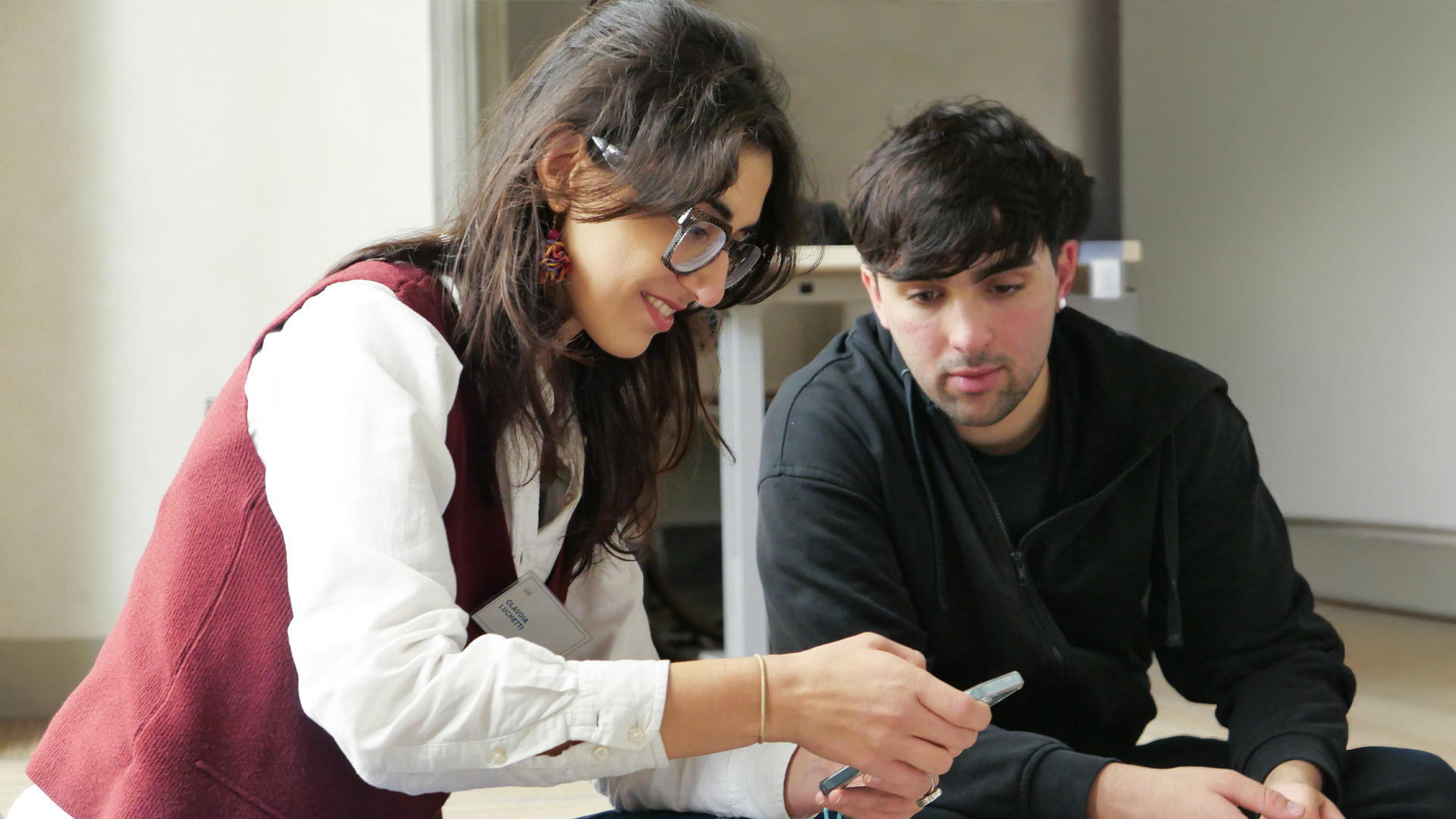 Research trainer and young participant sitting on the floor and looking at a mobile screen