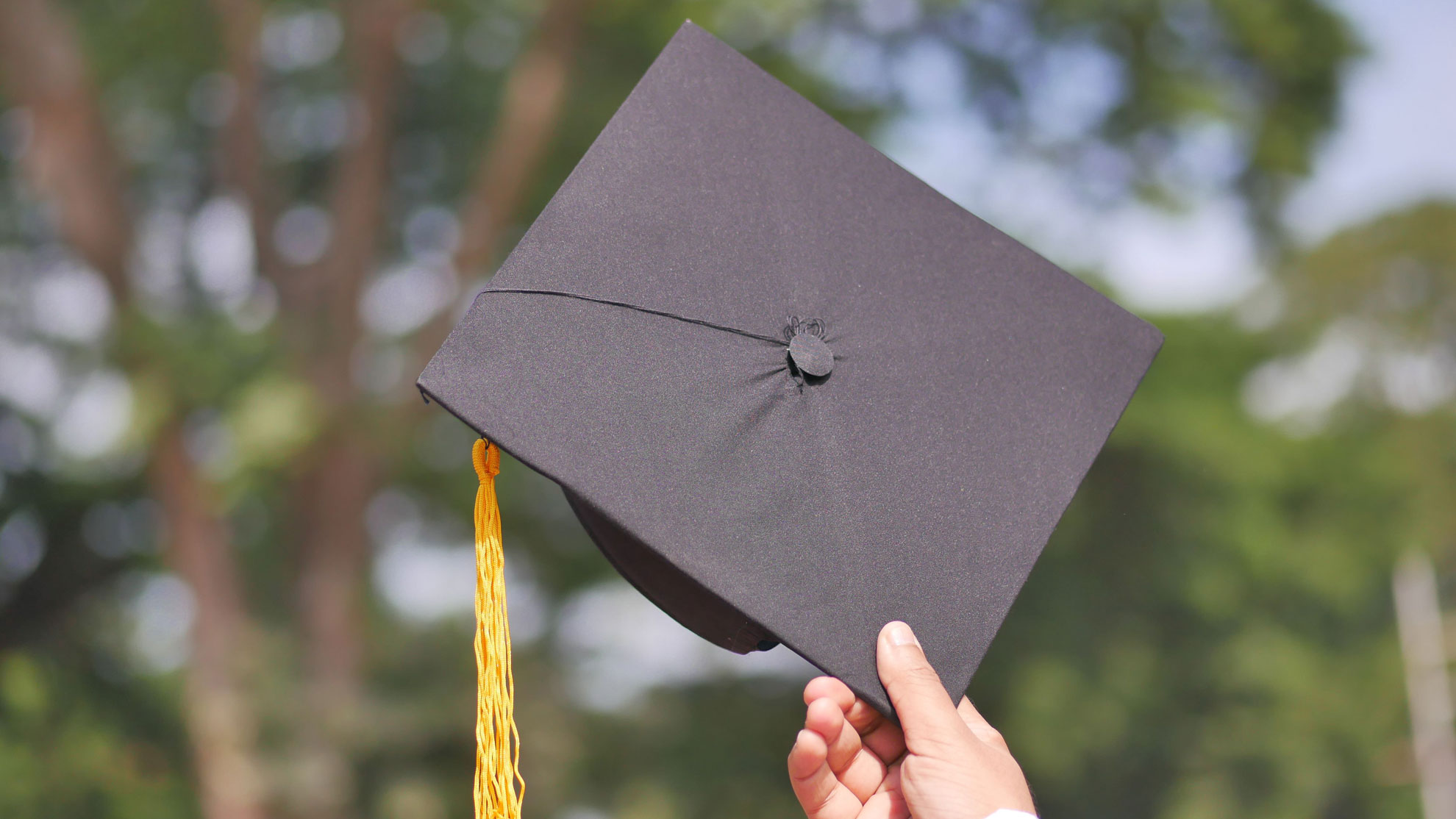 A hand holding a graduation cap, symbolizing achievement and celebration.