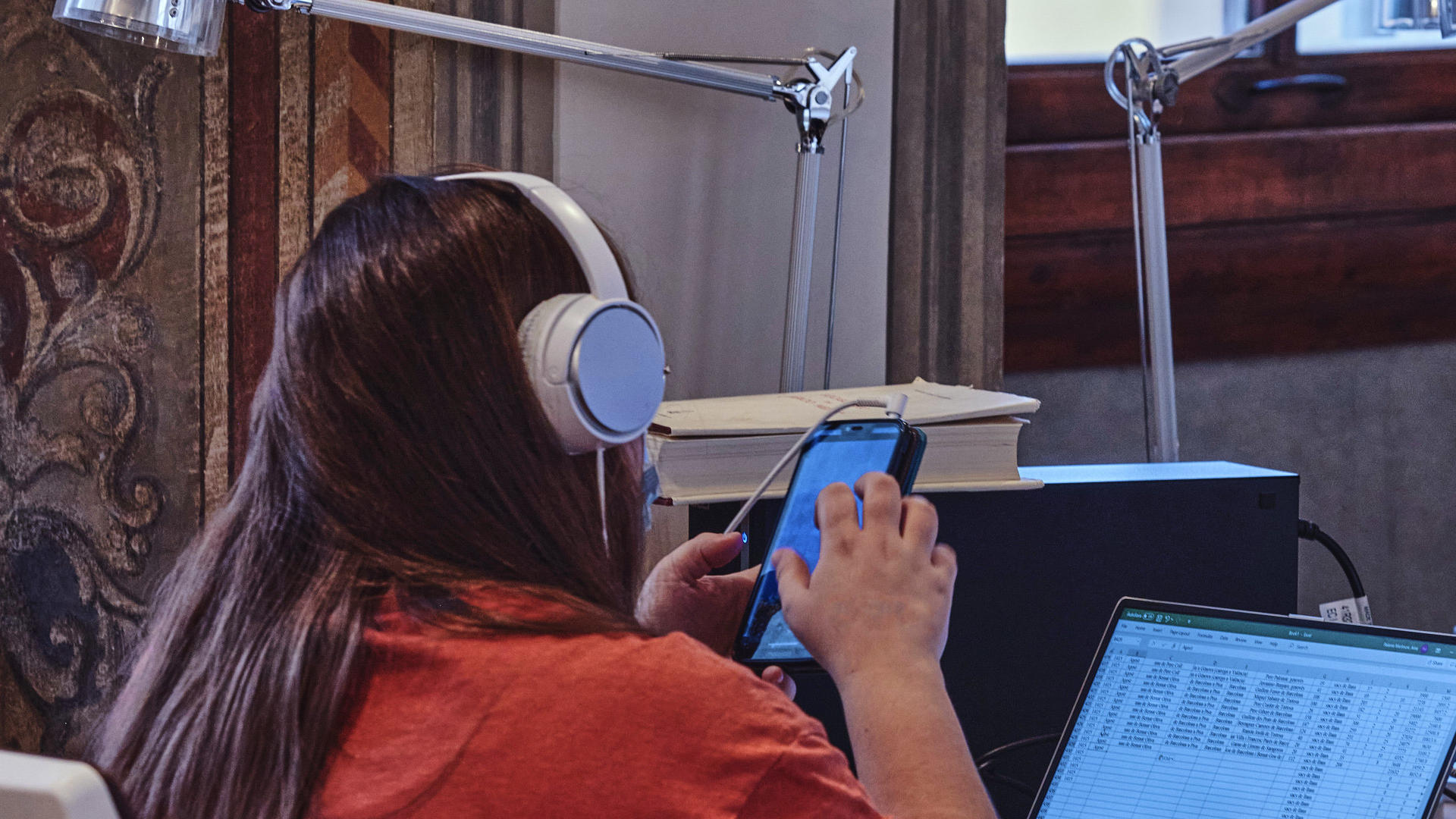Researcher with headphones using a phone, laptop and PC. 