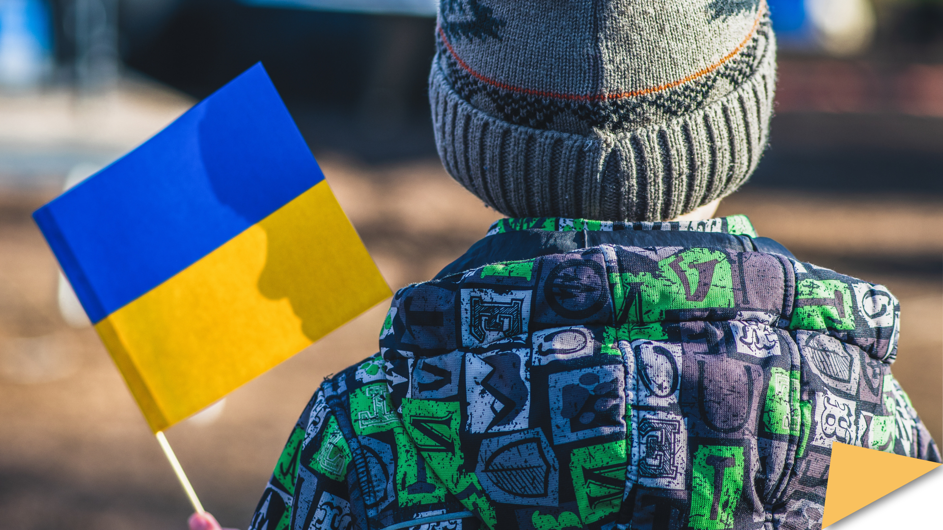 Young boy photographed from behind holding a Ukrainian flag
