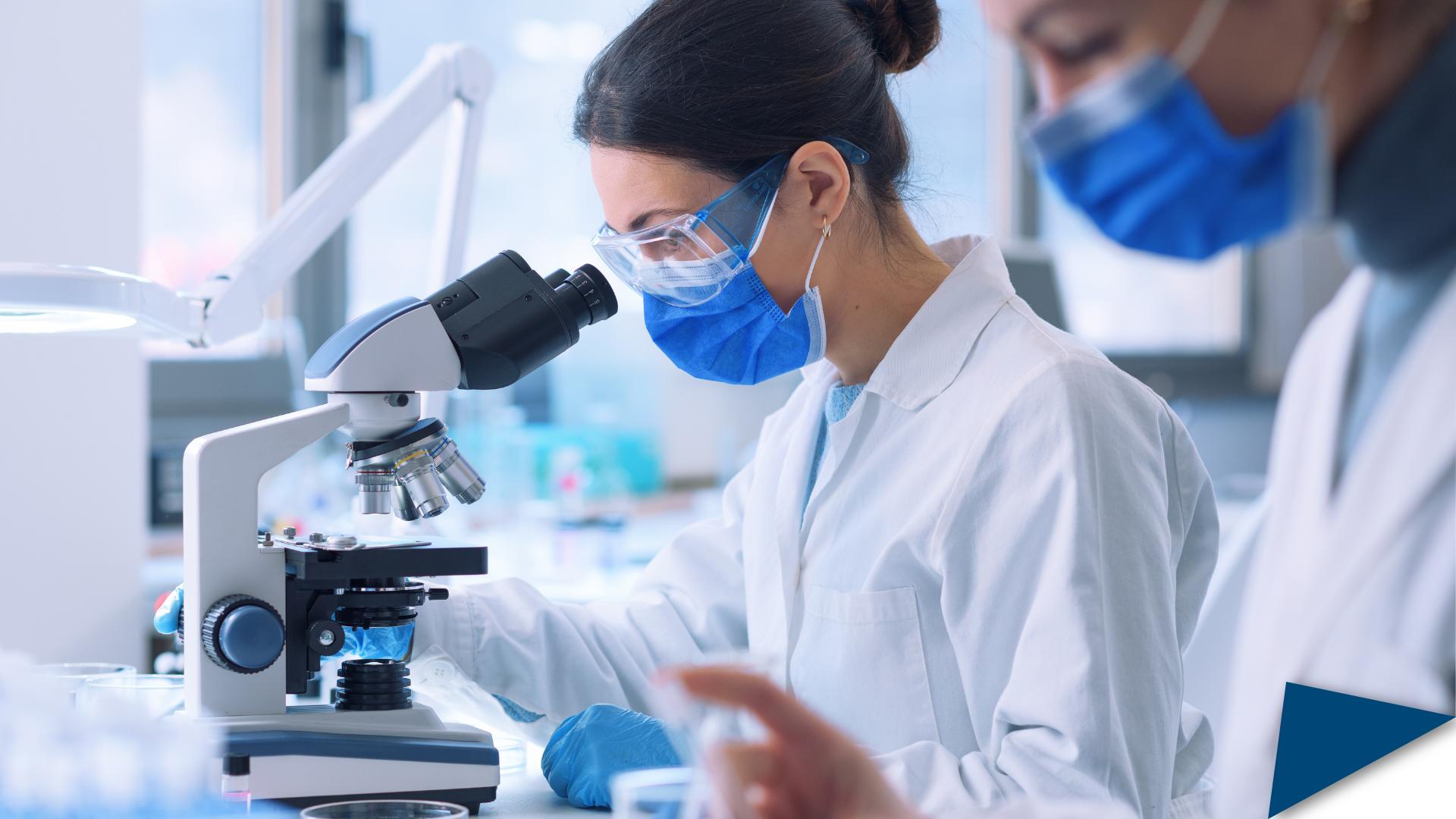 Women scientists in a lab, with one looking at a microscope