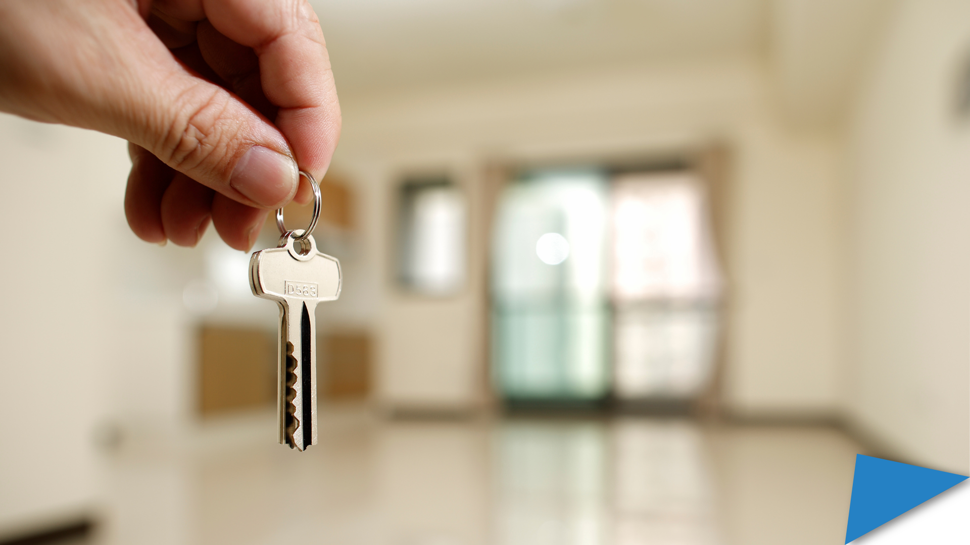 A hand holding a pair of keys to a rental house in the blurry background.