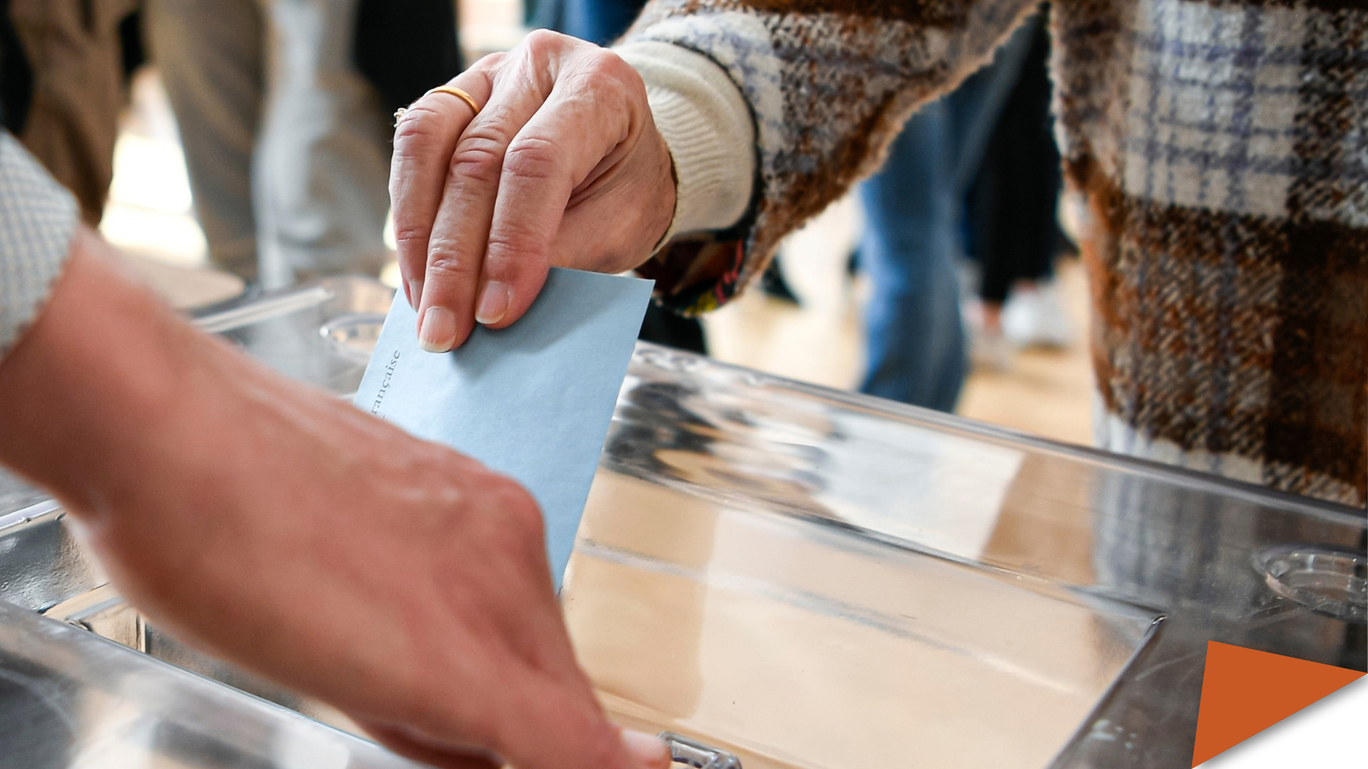 A ballot paper in its envelope, held in the hand by a lady, just before being placed in the ballot box.