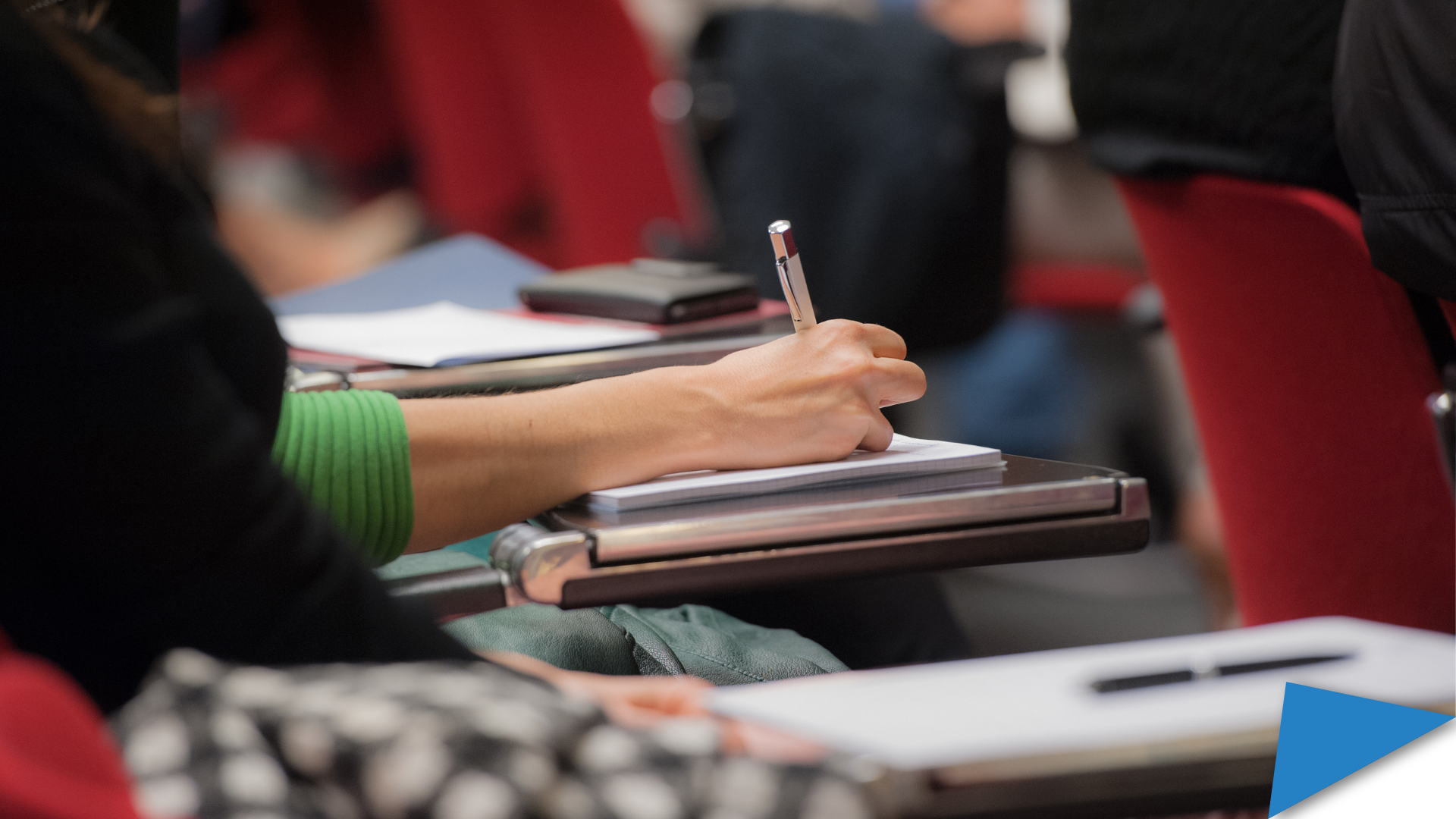 Student in a classroom, focus on the hand writing on a piece of paper.