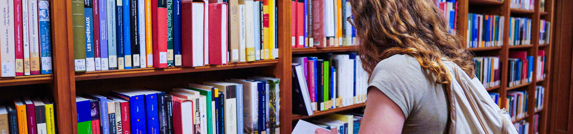 Student leafing through a book in the Library