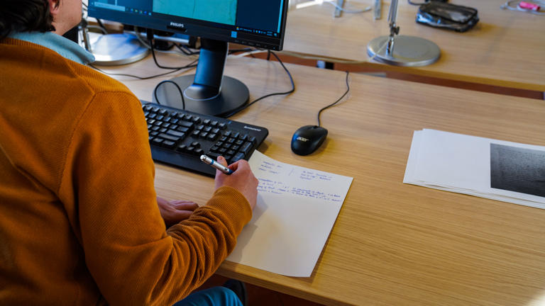 researcher-taking-notes-looking-at-a-screen.jpg